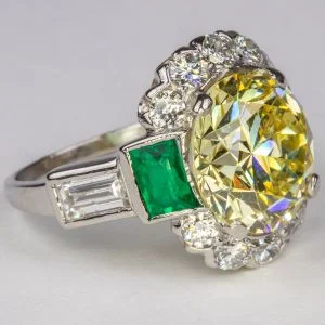 A fancy yellow diamond, emerald and platinum ring. Sold $55,000
